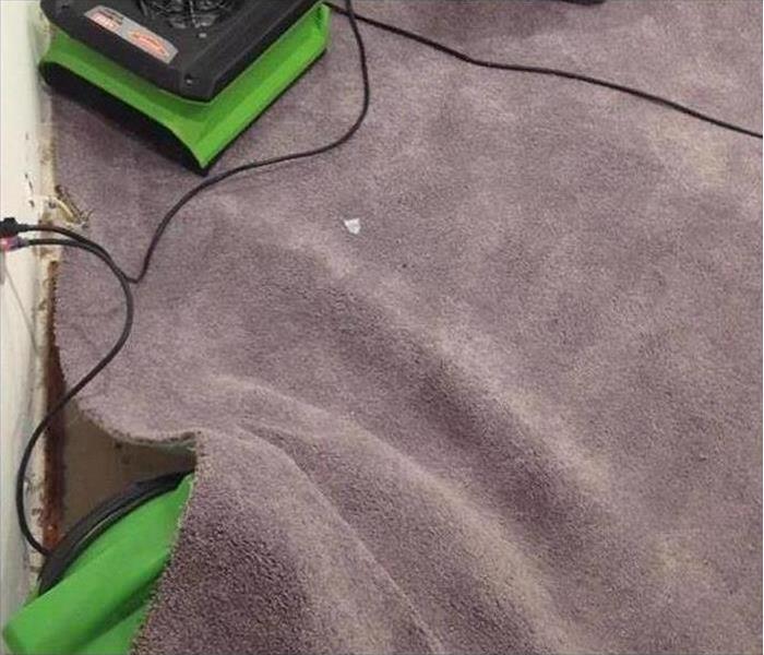 SERVPRO drying equipment inserted in floated carpeting to dry the carpet and padding