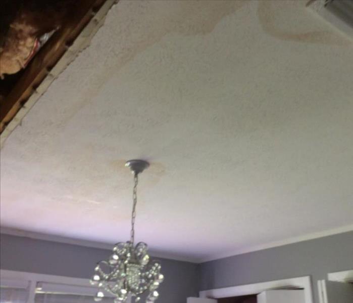 water stained ceiling, chandelier hanging and exposed attic area with insulation showing