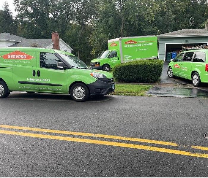 Three SERVPRO vehicles parked driveway and street
